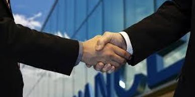 Two businessmen shaking hands in front of a finance building.