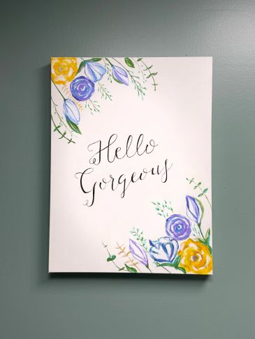A floral-decorated sign with the words 'Hello Gorgeous' in elegant calligraphy.