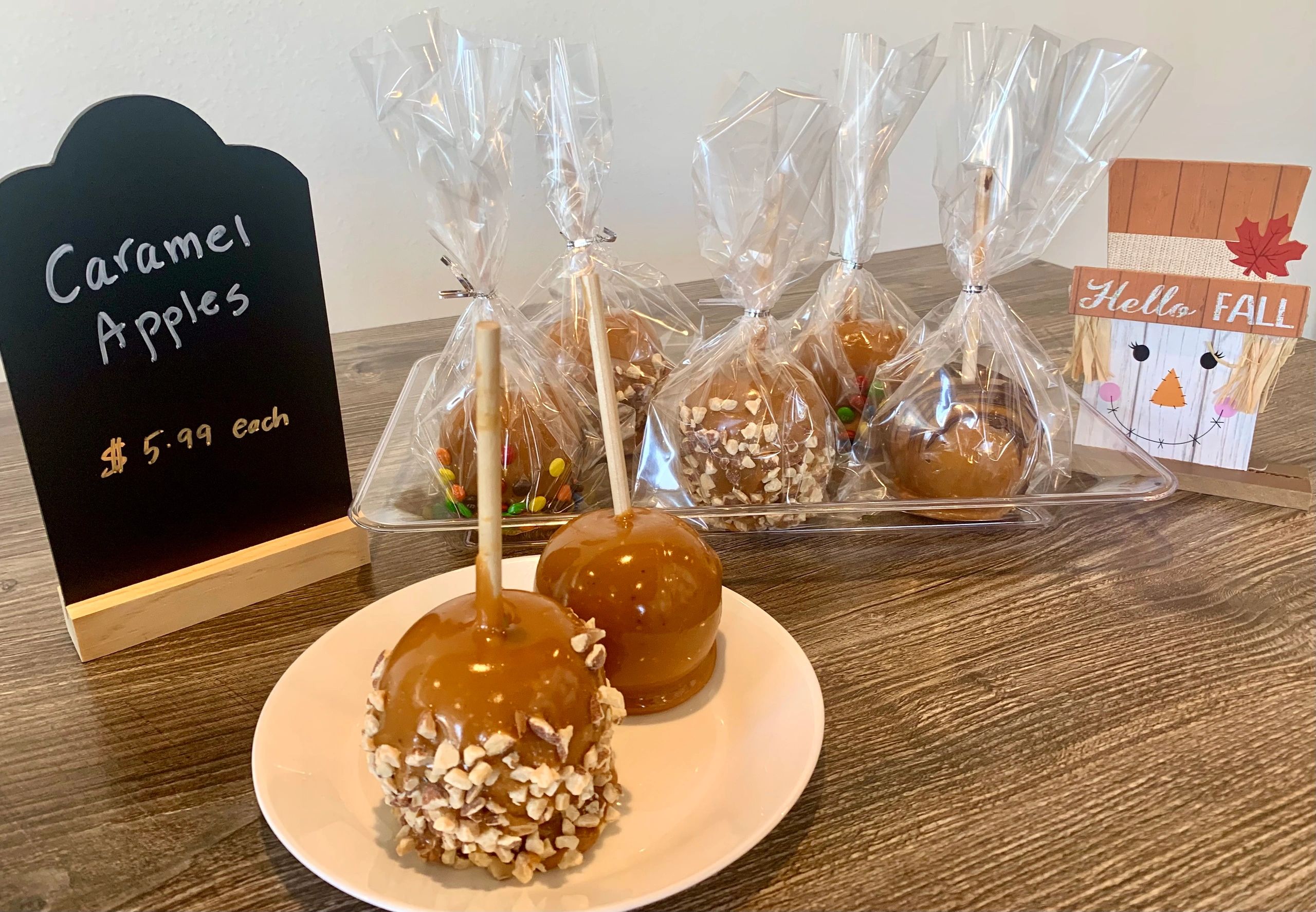 Caramel apples with fall-themed decoration and price sign.
