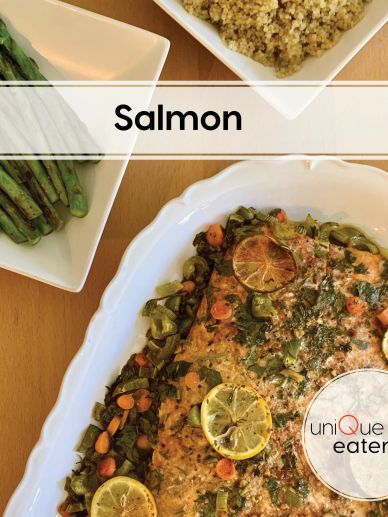 Baked salmon garnished with lemon slices, served with asparagus and quinoa.