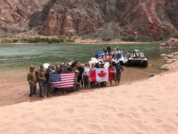 The 16-person crew at the Colorado River in the Grand Canyon, holding up the USA and Canada Flags