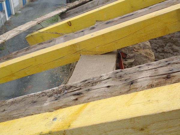 Yellow wooden beams on an old roof under construction in a rural area.