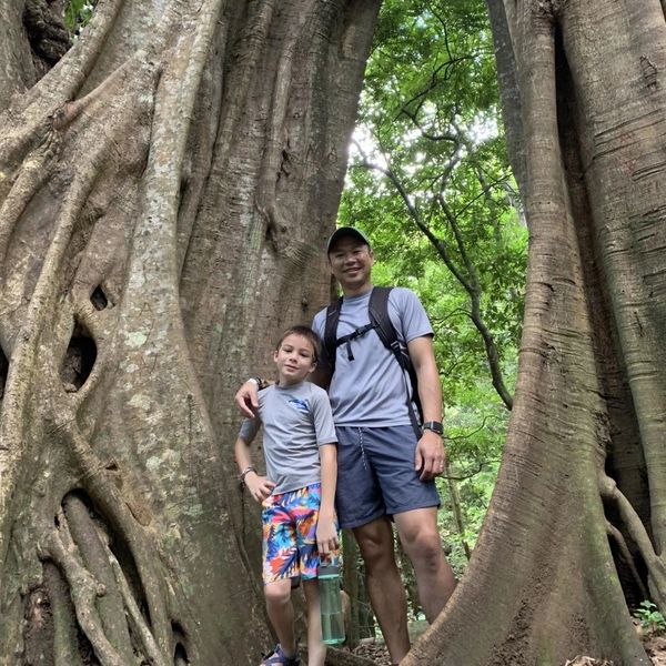 Father and son next to large tropical trees in Costa Rica.