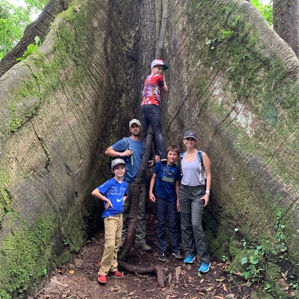 Family of five standing in front of a giant tree during a hike in Costa Rica.