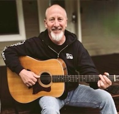 Smiling man playing acoustic guitar.