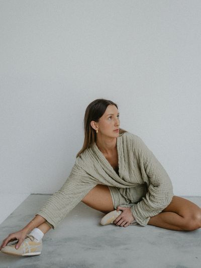 Woman stretching on floor in cozy textured outfit and sneakers.