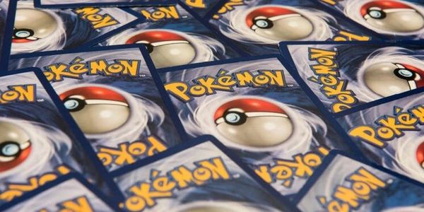 A scattered pile of Pokémon trading cards showing the back design with Poké Balls.