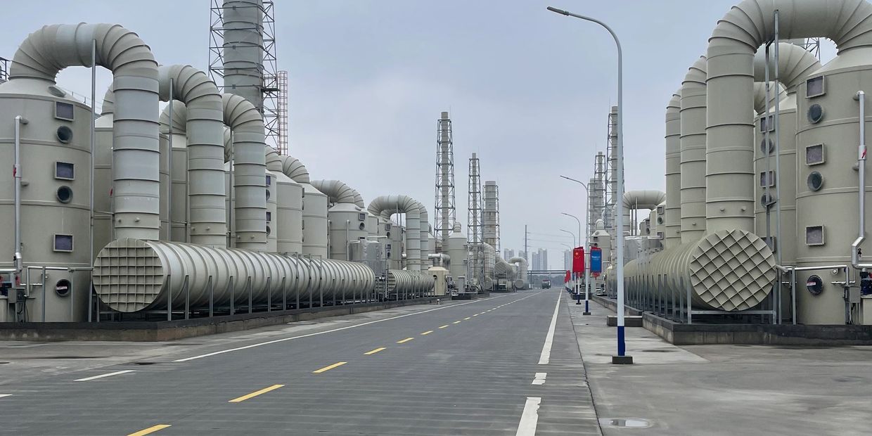 Industrial facility with large ventilation pipes and towers under a cloudy sky.