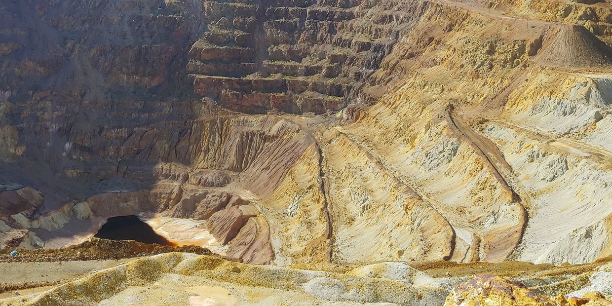 Open-pit mine with terraced layers under a clear sky.