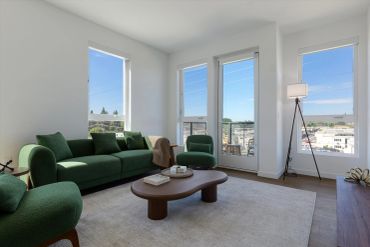 Bright living room with green furniture and large windows.