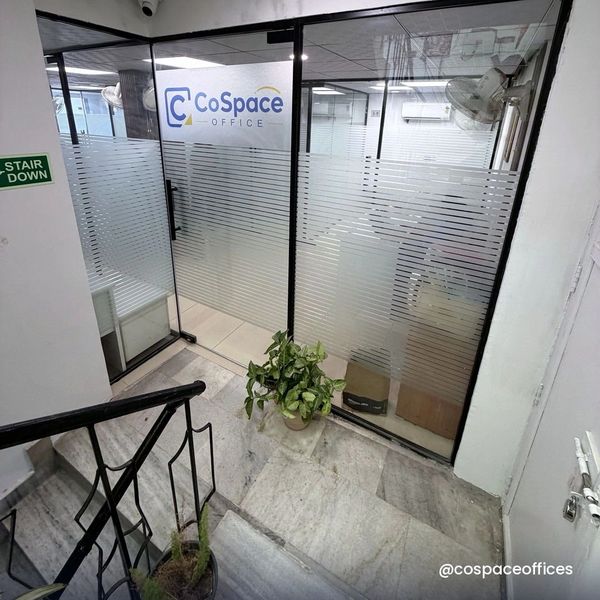 Entrance to a modern office space with glass doors and plants.
