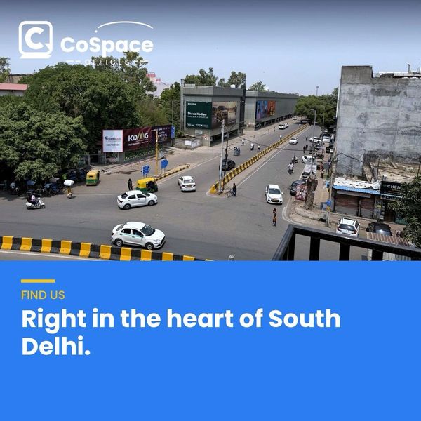 Busy intersection in South Delhi with cars and billboards.