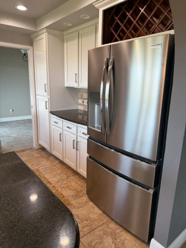 Modern kitchen with stainless steel fridge and white cabinets.
