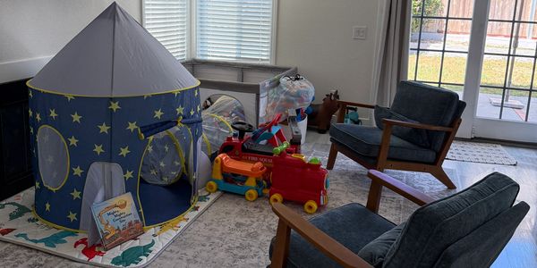 Children's play area with tent, toys, and chairs.