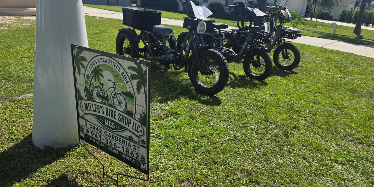 Sign for Miller's Bike Shop with bikes on grass.