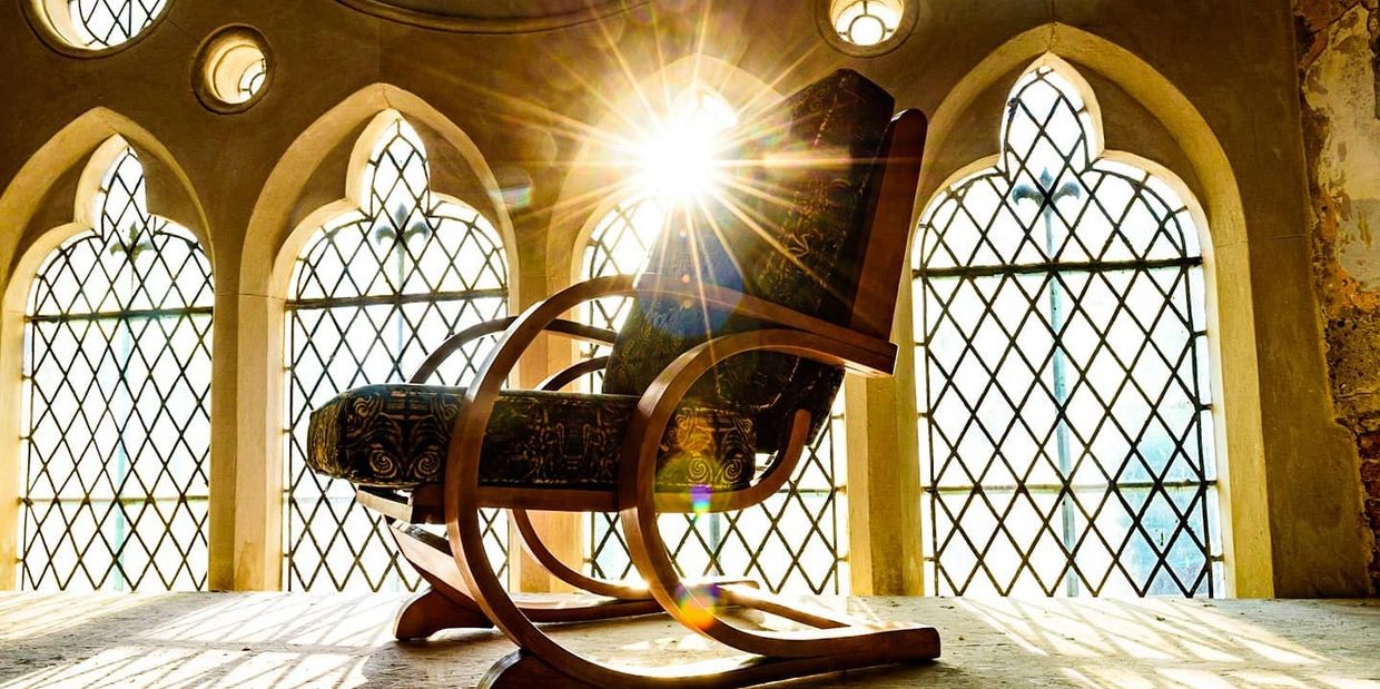Sunlight shining through stained glass behind rocking chair.