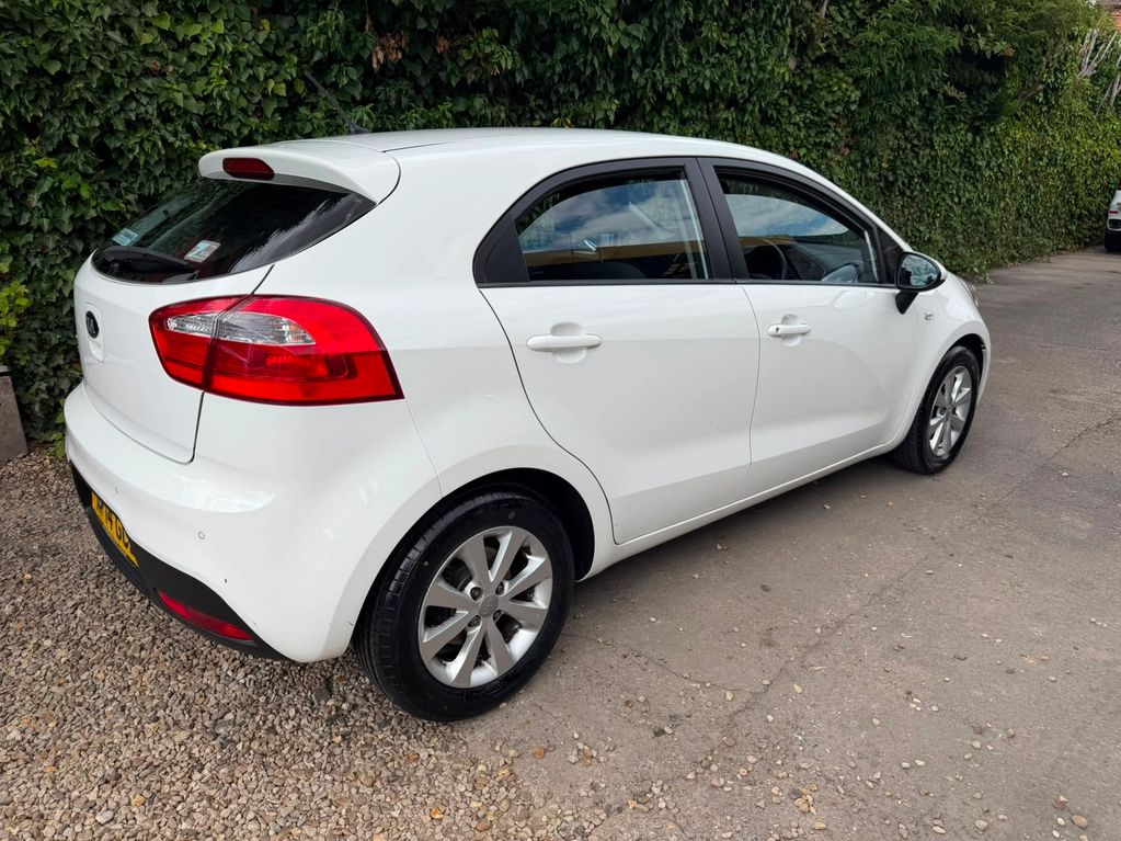 White compact car parked near green bushes.