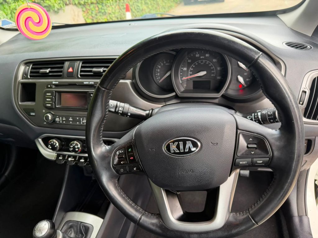 Interior view of a Kia car steering wheel and dashboard.
