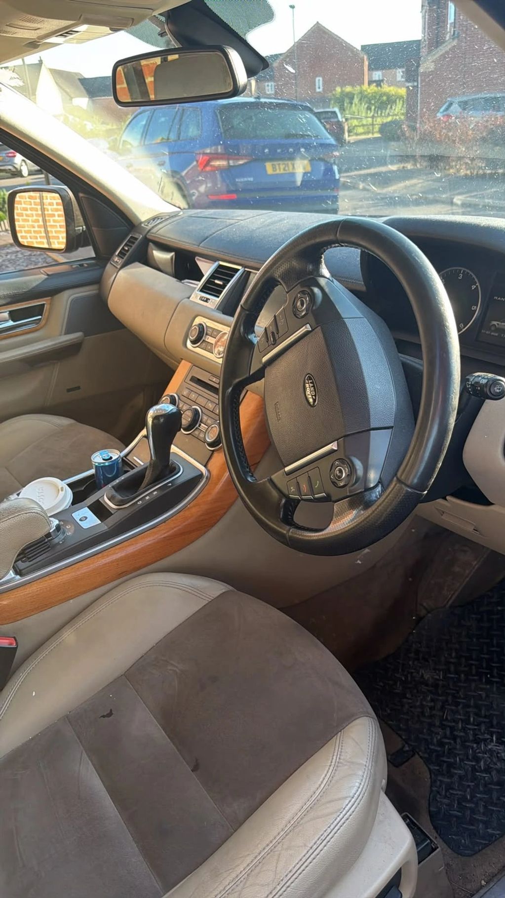 Interior of a Land Rover car with beige seats and wooden trims.