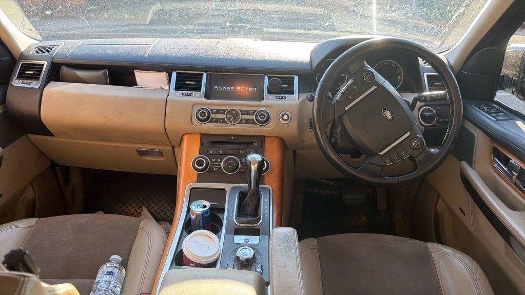 Interior dashboard of a Range Rover with drinks and water bottle.