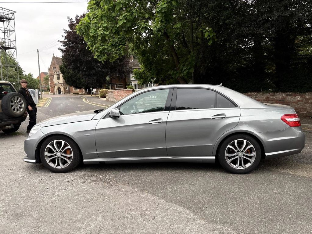 Silver sedan parked on a street with a person nearby.