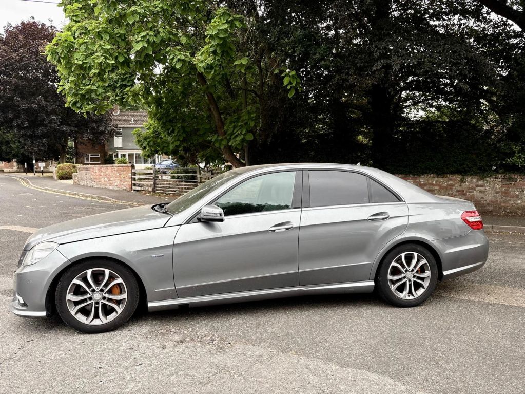 Silver sedan parked on the street under trees.