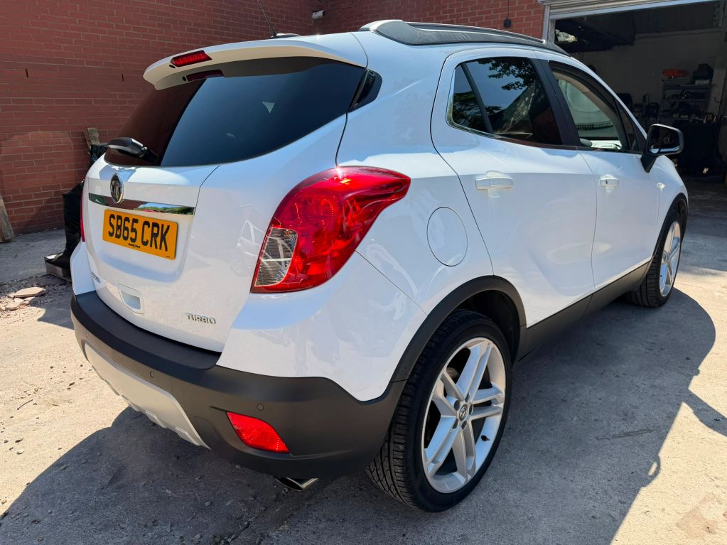 White compact SUV parked outside a garage.