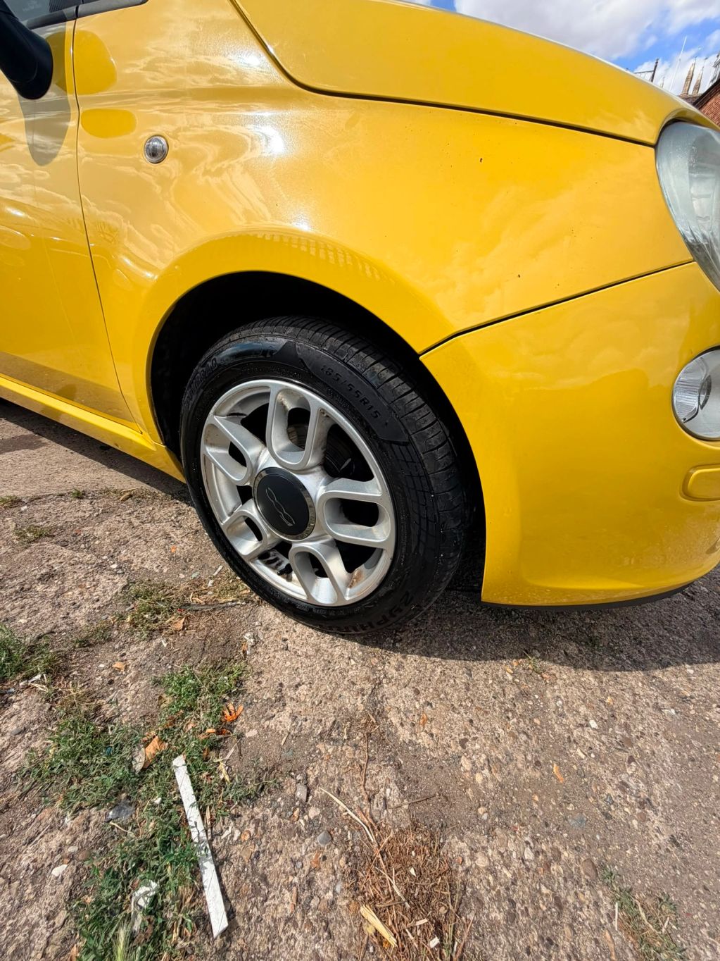 Close-up of a yellow car's front side and tire.
