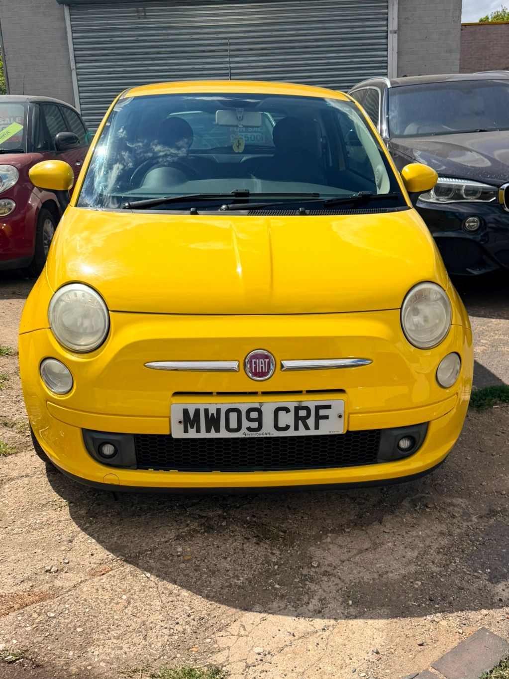Front view of a bright yellow Fiat 500 car.