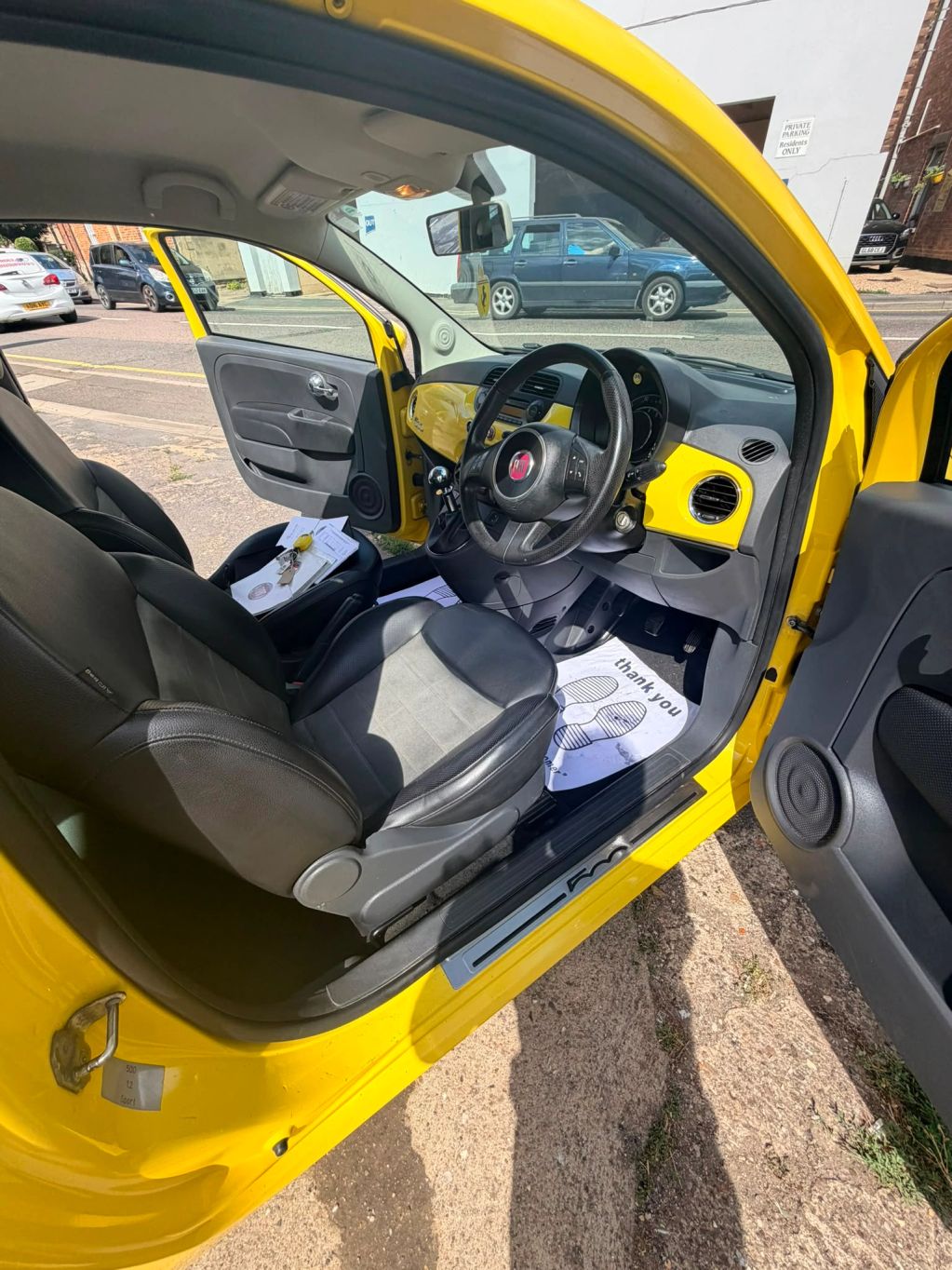 Interior view of a yellow Fiat car with doors open.