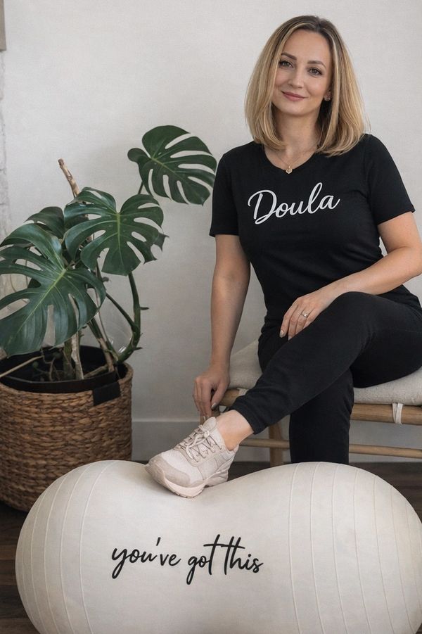 Professional birth doula sitting on a birthing ball in a calm, modern space