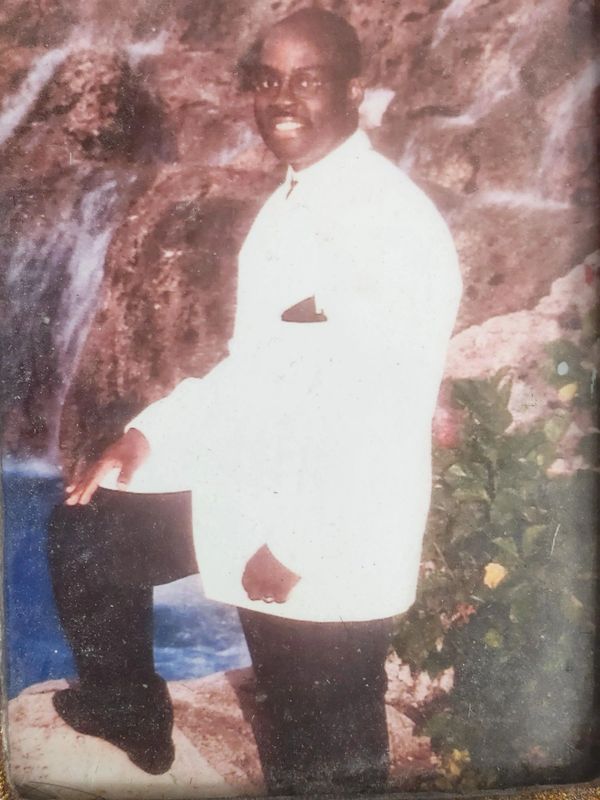 Portrait of a distinguished African American man dressed in a white suit, posing confidently 