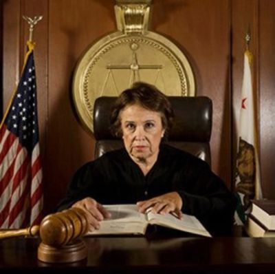 Female judge in courtroom with gavel and flags.