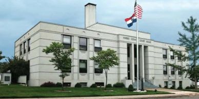Exterior view of a government building with flags and landscaping.