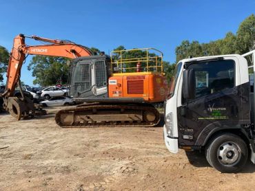 Orange excavator and white truck parked on dirt.
