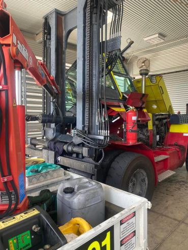 A red forklift with hydraulic cables in a garage.