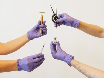 Hands in purple gloves holding medical and measuring tools.