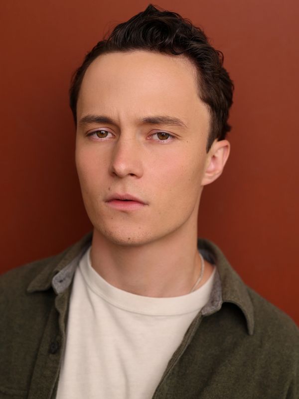 Serious young man against a brown background.