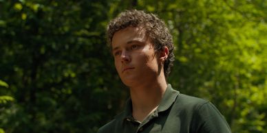 Young man with curly hair standing outdoors.