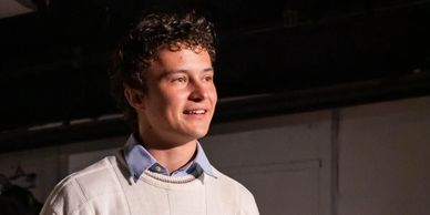 Young man with curly hair smiling.