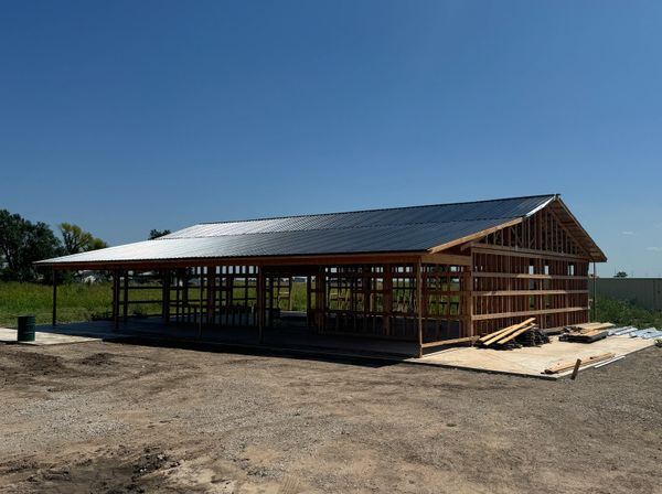 Partially constructed wooden building under clear blue sky.