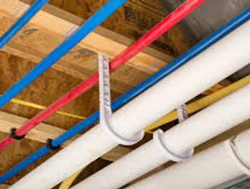 Color-coded pipes secured to a wooden ceiling with metal hangers.