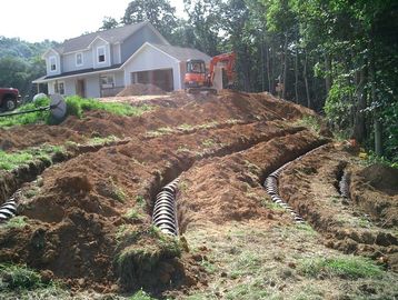 Excavation for drainage pipes near a house under construction.