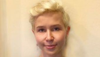 Portrait of a person with short blonde hair and a neutral expression.