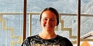 Smiling woman in front of a window with mountain view.