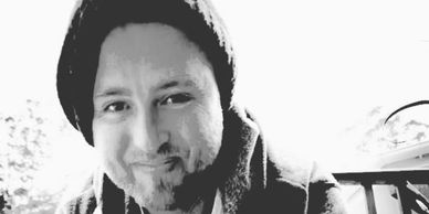 Smiling man wearing a beanie in black and white photo.