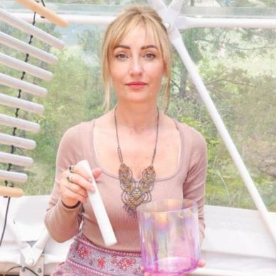 Woman holding a white object inside a bright greenhouse.