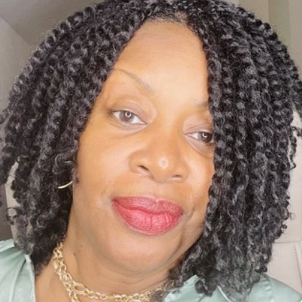 Close-up portrait of a woman with curly black hair and red lipstick.