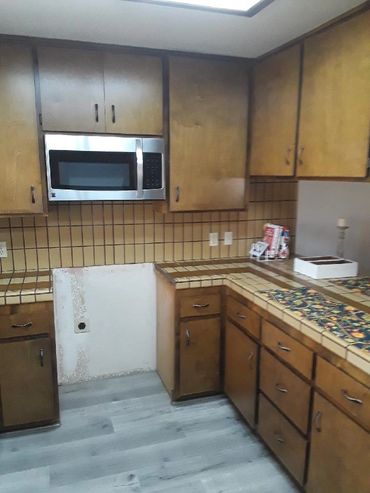 Old kitchen with wooden cabinets and missing appliance.