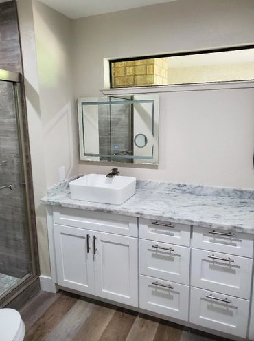 Modern bathroom vanity with white cabinets and marble countertop.